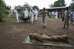 Liberische Krankenhelfer und Ärzte tragen ein Ebola-Opfer. Dieses soll in der Banjor Community am Rande von Monrovia beerdigt werden. (Bild: Keystone)