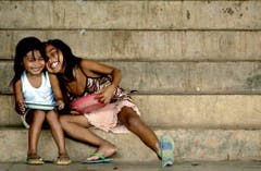 Zwei Mädchen lachen während des Essens in einem Evakuierungscamp auf den Philippinen am 26. Mai 2003. (Bild: Keystone)