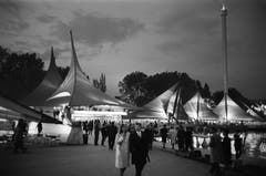 Besucher flanieren an der Expo 64 in Lausanne über das Gelände: Neben Ausstellungszelten ist rechts der markante Aussichtsturm, genannt die Spirale, zu sehen. (Bild: Keystone / Str)