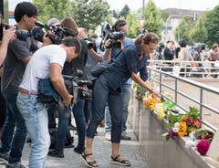 Trauern in der Öffentlichkeit: Eine Frau legt Blumen nieder. Zahlreiche Journalisten halten diesen Moment mit ihren Kameras fest. (Bild: Keystone / Sebastian Widmann)
