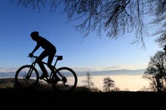 Biker im Gegenlicht über dem Nebelmeer am Pfannenstiel in Zürich. (Bild: Keystone)