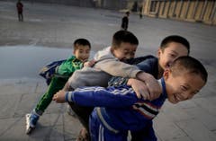 Nordkoreanische Jungs versuchen sich während des Inlineskatens zu fangen und brechen dabei in Gelächter aus. (Bild: Keystone)