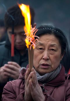 Andächtig betet eine Chinesin, während sie Weihrauch abbrennt. (Bild: Keystone)
