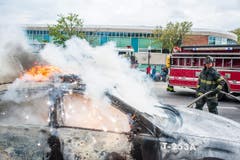 Ein brennendes Polizeiauto wird gelöscht. (Bild: Keystone/EPA/Noah Scialom)