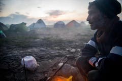 Ein Mann wärmt sich an einem Feuer im Aufnahmelager in Idomeni an der griechisch-mazedonischen Grenze. (Bild: Keystone)