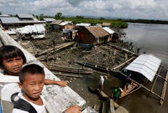 Zwei philippinische Schulkinder vor den zerstörten und notdürftig wieder aufgebauten Hütten in ihrem Dorf in der östlichen Provinz Samar. (Bild: Keystone)