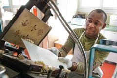 Nduka Anaenyonu alias «Charlie» arbeitet an der Backmaschine. Gut auf der Presse zu sehen sind die Muster, die den Hostien das wunderbare Aussehen verleihen. (Bild: Dominik Wunderli / Neue LZ)