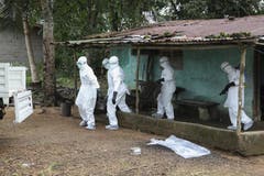 Nachdem sie ein Ebola-Opfer aus diesem Haus holten, desinfizierten diese liberianischen Einsatzkräfte das Gebiet rund um das infizierte Haus. (Bild: Keystone)