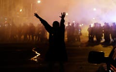 Vor dem Polizeikordon macht sich ein Demonstrant davon. (Bild: AP Photo / David Goldman)
