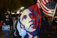 Ein Mann schwenkt vor dem Weissen Haus in Washington eine Obama-Fahne. (Bild: Keystone)