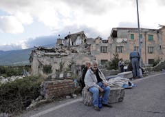 Bewohner von Amatrice vor eingestürzten Gebäuden. (Bild: AP / Alessandra Tarantino)