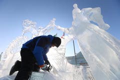 Ebenfalls in der Ferne: In der Eis- und Schneewelt in Harbin in Nordchina bearbeitet ein Künstler das gefrorene Material seines Werks. (Bild: EPA/WU HONG)