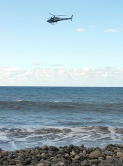 Ein Helikopter bei der Suche weiterer Hinweise über dem Strand von La Réunion. (Bild: Keystone)
