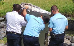 Französische Polizisten untersuchen das gefundene Wrackteil. (Bild: Keystone)
