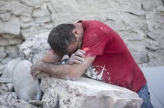 Ein Mann beugt sich über einen Trümmerstein in Amatrice. (Bild: AP / Massimo Percossi)