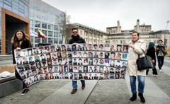 Vor dem Gericht in Den Haag verleihen Aktivisten der Forderung nach einer Verurteilung Nachdruck: Sie zeigen Bilder von Opfern des Krieges. (Bild: EPA/KOEN VAN WEEL)