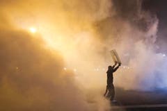In der Nacht auf Mittwoch wird ein Demonstrant in den Nebel von Rauchpetarden gehüllt. (Bild: AP Photo/Matt Rourke)