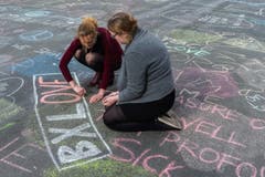 Auf dem Platz vor der Börse in Brüssel schreiben zwei Frauen ihre Botschaft der Solidarität. (Bild: AP Photo / Geert Vanden Wijngaert)