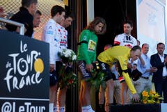 Fahrer der Tour de France legen bei der Siegerehrung Blumen nieder. (Bild: AP / Christophe Ena)