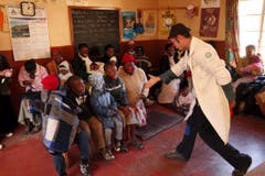 Der Clown Jamie Lachman (rechts)gibt am 10. Juli 2008 einem kranken Knaben in einer Klinik in Lesotho die Hand und versucht ihn zum Lachen zu bringen. (Bild: Keystone)