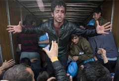 Ein verletzter Mann spricht mit der Menschenmenge, die sich in Idomeni vor einem Lastwagen mit Hilfsgütern versammelt hat. (Bild: Keystone)