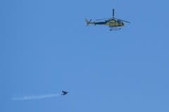 Yves Rossy, der "Jetman", fliegt mit seinem portablen Duesenantrieb neben dem Helikopter, der ihn in die Höhe transportierte. (Bild: Keystone)