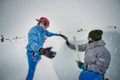Cedric Spirgi (links) und Jérémie Rothenfluh passen mit der Säge einen Schneeblock ein. (Bild: Pius Amrein / Neue LZ)