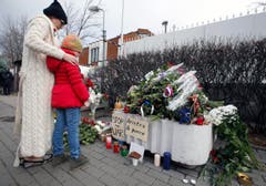 Eine Frau und ein Kind stehen vor den Blumen bei der französischen Botschaft in Moskau. (Bild: EPA/Sergei Chrikov)