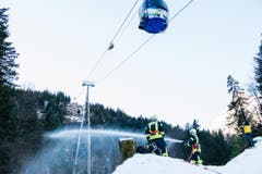 Während sich Retter zu den Gondeln abseilen, löscht die Feuerwehr den fiktiven Waldbrand. (Bild: Roger Grütter / Neue LZ)