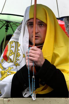 Während die Kardinäle in der Sixtinischen Kapelle wählen, betet dieser Mann auf dem Petersplatz - in eine Flagge gehüllt und mit einem Rosenkranz in der Hand. (Bild: Keystone)