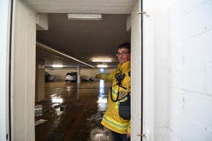 Feuerwehrkommandant Andreas Bösch steht im Türrahmen und zeigt auf die Türe. Das Wasser drückte sie ein und schleuderte sie durch die Tiefgarage. Das, obwohl die Türe sich gegen das Wasser geöffnet hätte. (Bild: Manuel Nagel)