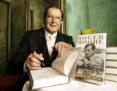 Roger Moore unterschreibt sein Buch "The World is My Bond" während einer Pressekonferenz 2008. (Bild: Keystone)