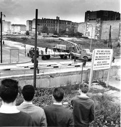 Westberliner schauen am 12. September 1961 an der Wilhelmstrasse in Berlin der Anlieferung vorgefertigter Betonbauteile zur Verstärkung der Berliner Mauer zu. (Bild: Keystone)