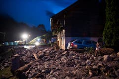 Erdmaterial, Steine und Holz blockieren eine Strasse. (Bild: Keystone)