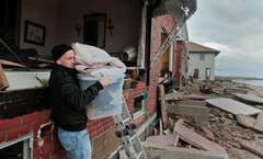 Peter Andrews bringt die Habseligkeiten aus dem zerstörten Haus seines Vaters. Andrews: «Wir haben schon viele Stürme erlebt und der einzige Schaden bisher entstand, als ein Mann der Nationalgarde einen Sandsack durch das Fenster warf.» (Bild: Keystone)