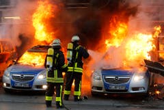 Feuerwehrleute löschen brennende Polizeiautos. (Bild: Keystone)