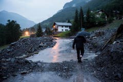 Ein Mann auf einer teils verschütteten Strasse in Schwendi. (Bild: Keystone)