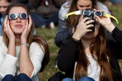 Nur mit Schutzbrille kann man überhaupt etwas sehen von der Sonnenfinsternis. (Bild: Keystone)