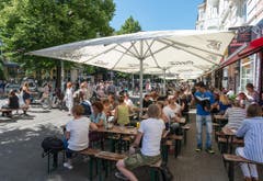 Menschen essen vor der roten Flora in Hamburg und geniessen die Ruhe und das Wetter während das Viertel von Anwohnern aufgeräumt wird. (Bild: Keystone)