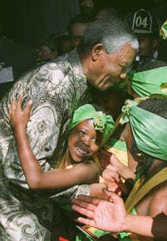 Sie nennen ihn liebevoll "Madiba": Nelson Mandela wird von einem Schulmädchen umarmt (1997). (Bild: Keystone)