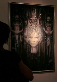 Ein Besucher betrachtet ein Giger-Bild an einer Ausstellung. (Bild: Keystone)