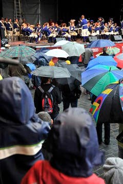 Fast mehr Regenschirme als Musiker: ein Bild, das sich bei Präsentationen in der Innenstadt am Samstag mehrfach zeigte. (Bild: Keystone)