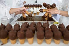 Mitarbeiter von Gasparini tauchen Rahmglaces in flüssige Schokoladenmasse. Das "Zolli-Cornet" wird in Münchenstein im Kanton Basel-Land produziert. (Bild: Keystone)