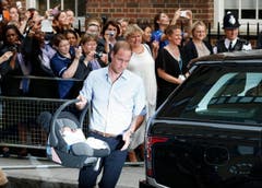Da hat wohl jemand heimlich geübt: Prinz William spediert die Trage mit seinem Sohn gekonnt ins Auto. (Bild: Keystone)