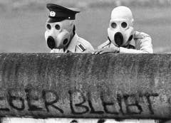 Mit Gasmasken ausgerüstet blicken DDR-Grenzsoldaten am 21. Juni 1988 über die Mauer am Potsdamer Platz in Berlin. (Bild: Keystone)