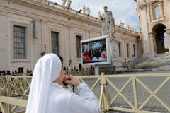 Eine Nonne verfolgt die Wahl-Messe der Kardinäle auf einer Leinwand vor der Petersbasilika. (Bild: Keystone)
