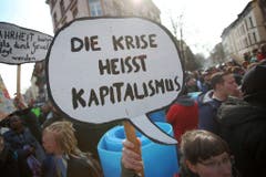 "Die Krise heisst Kapitalismus" steht auf dem Plakat einer Demonstrantin. (Bild: Keystone)