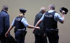 Einsatzkräfte führen zwei Angehörige von Absturzopfern in einen geschützten Bereich des Düsseldorfer Flughafens. (Bild: Keystone)