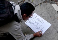 Ein Unterstützer Chávez' schreibt ein Schild. (Bild: Keystone)