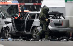 A bomb disposal specialist in protective gear passes by an exploded car as he investigates the site of the blast in Berlin, eastern Germany, Tuesday, March 15, 2016. (AP Photo/Michael Sohn) (Bild: Keystone)